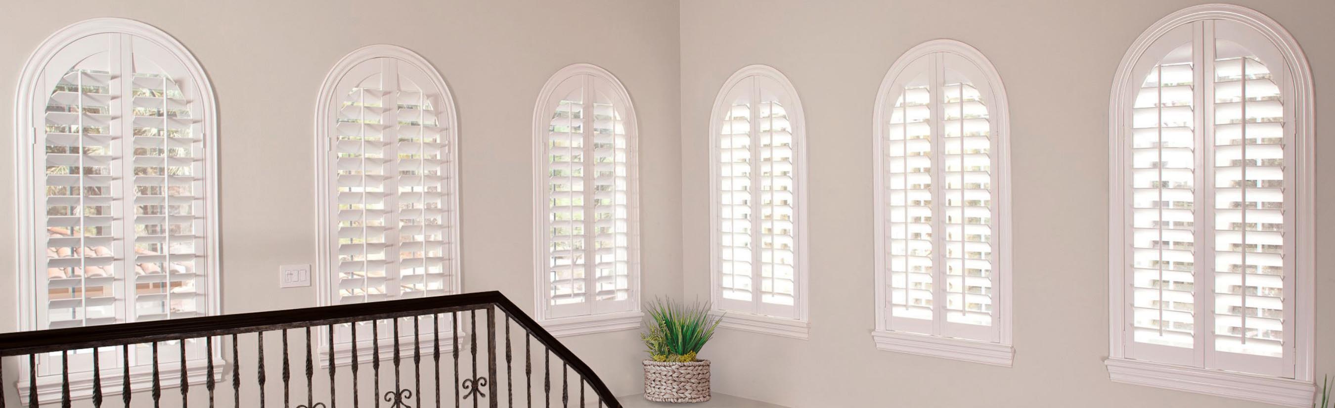 White arched shutter windows by a stairwell.