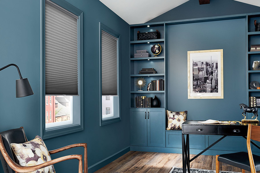 Thick window shades hide outside distractions and give you privacy while you work. Gray cellular shades on windows in a blue home office