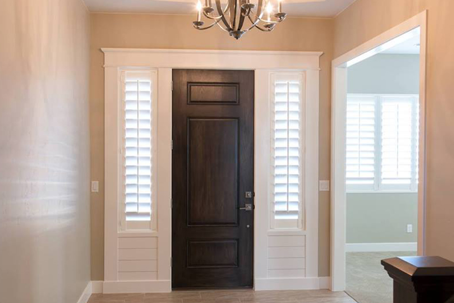White Polywood shutters are a great, durable window treatment option for energetic dogs. White shutters on sidelights.