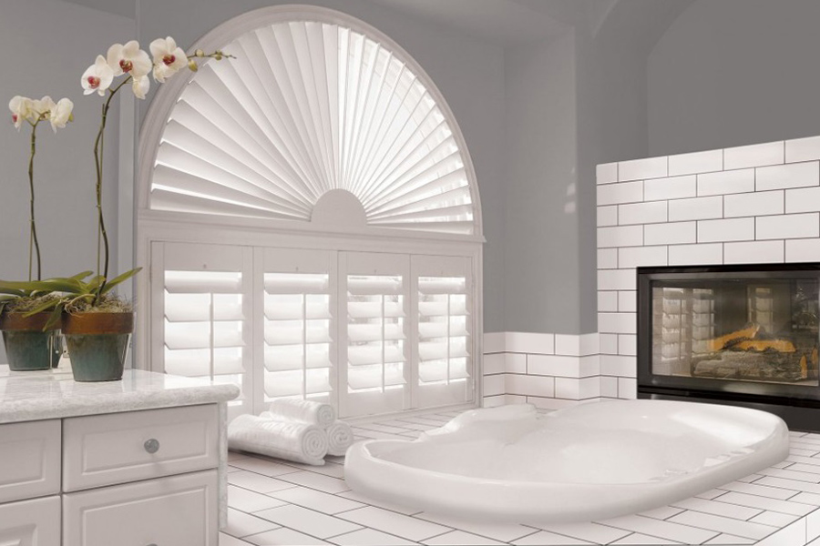 Customize your windows with elegant Polywood shutters. White Sunburst Polywood shutters in a large white bathroom