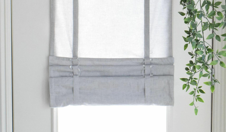 With a tiered tumble shade in Las Vegas, you can block sun glare all year round. Gray rolled tumble shade on a glass door